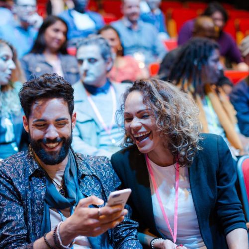 Man and woman with smart phone in conference audience