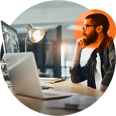 stylized graphic showing a young male worker at his desk, in front of laptop and large display, thinking about something on the screen.