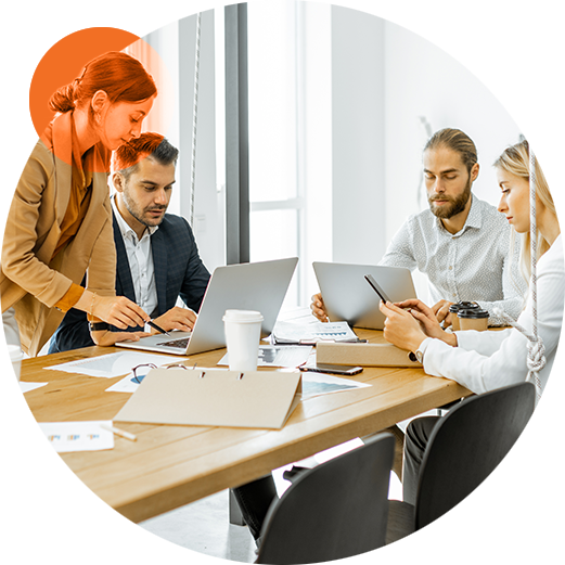 four coworkers sitting around a conference table in a modern, open office having a meeting.